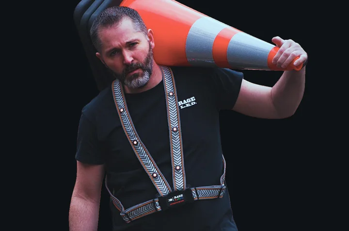 Rage LED RSV-1 lighted safety vest with flashing LEDs, worn by a worker carrying a traffic cone